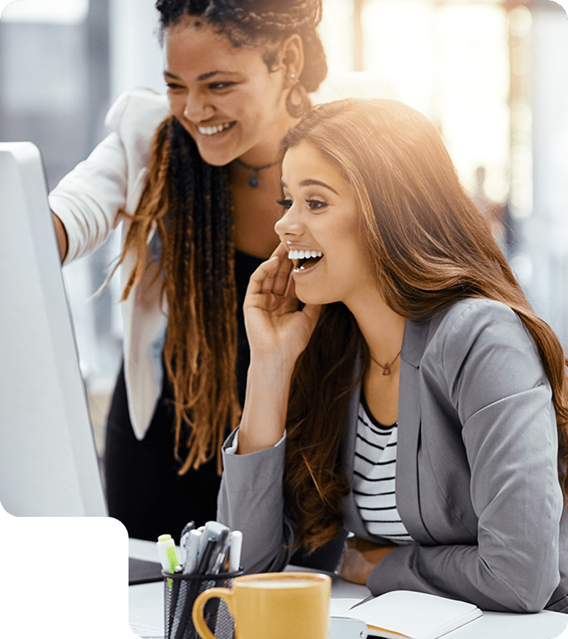 two females looking suprised staring at a computer screen